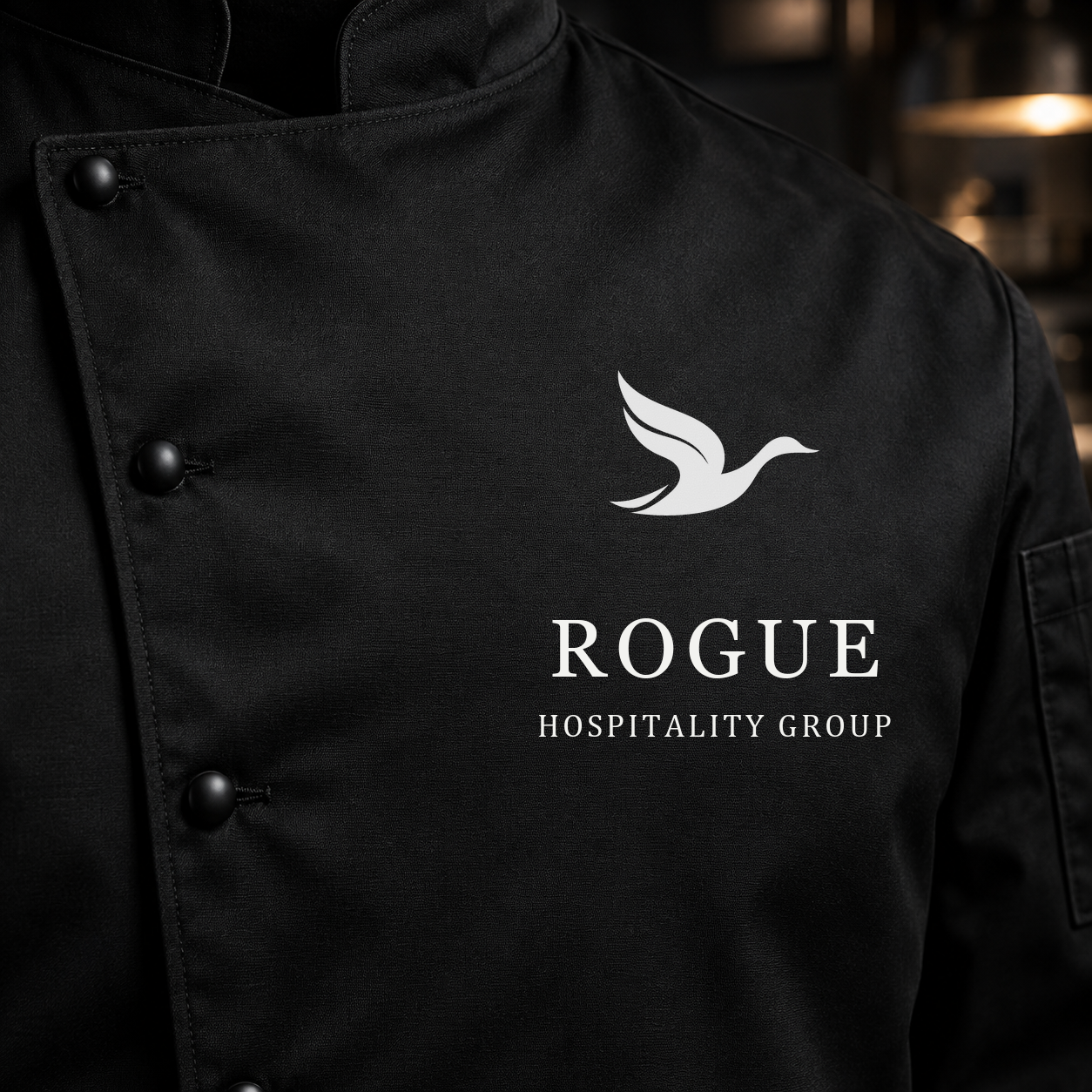 A black chef coat embroidered with the Rogue duck mark